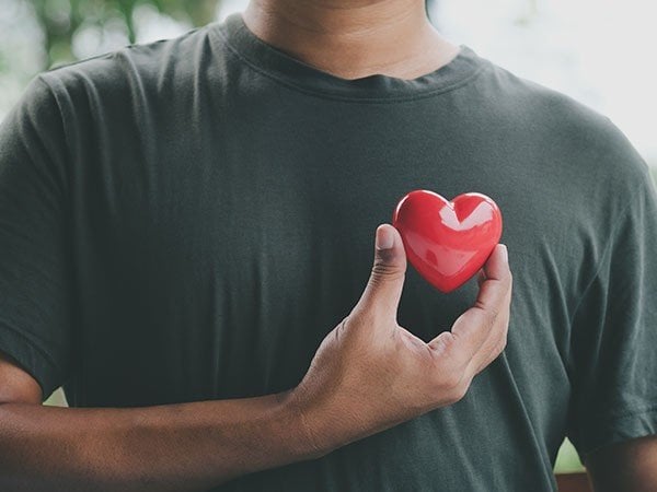 Man in a green shirt holding a small red heart