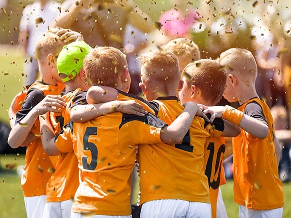 Youth soccer team in yellow jerseys huddling together on a field